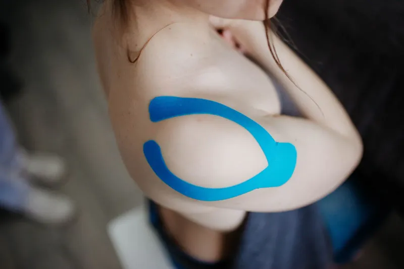 Modrý kinesio tejp nalepený na rameni
