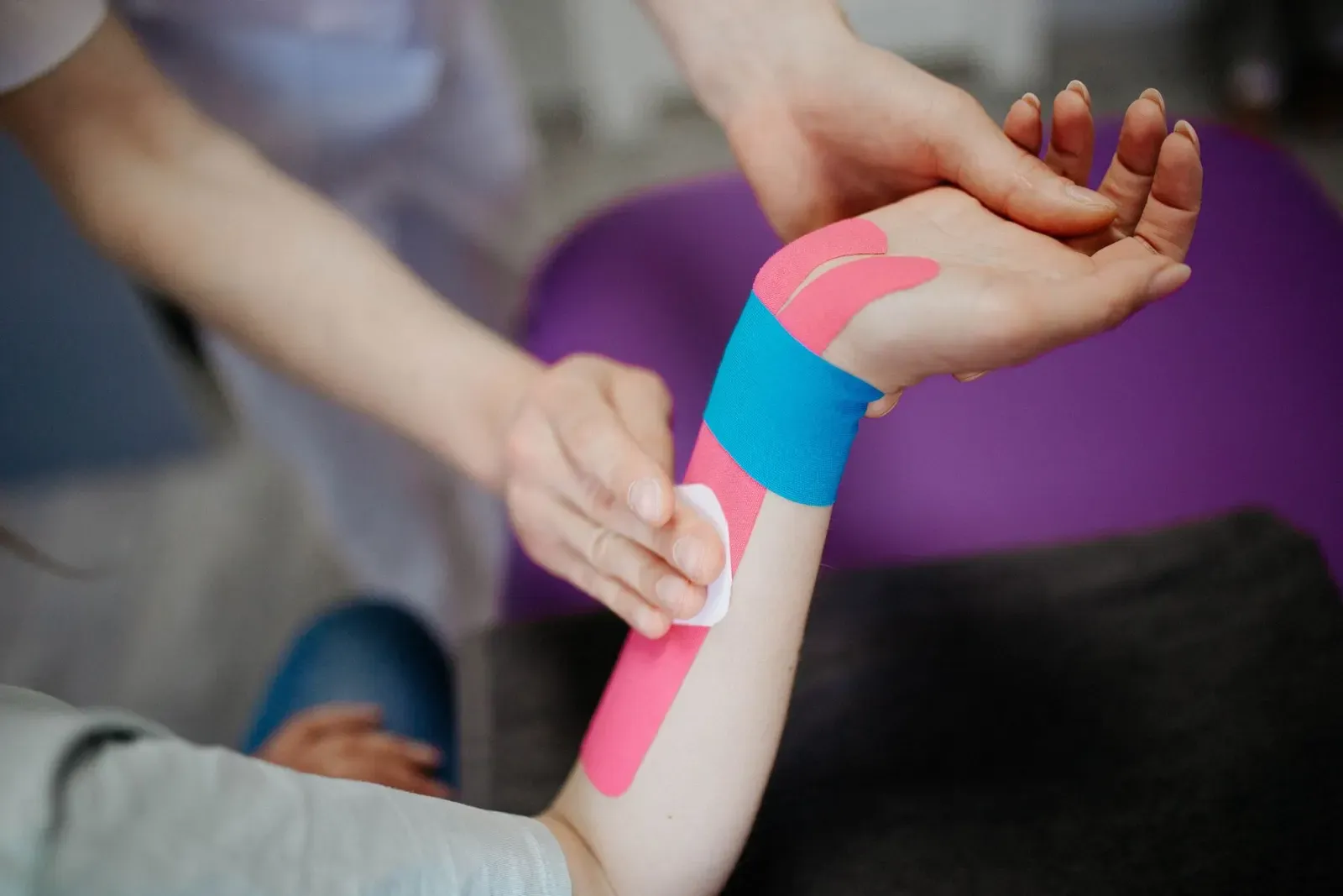 Růžový a modrý kinesio tejp na předloktí a zápěstí