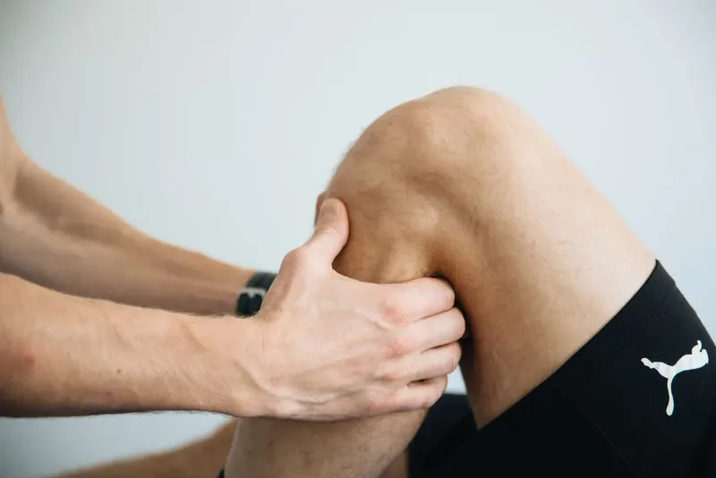 Ruce fyzioterapeuta při ošetření kolena